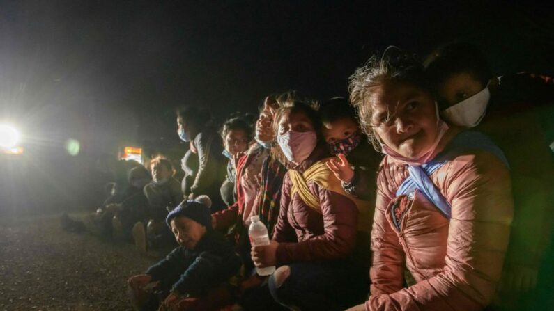 Mujeres y niños inmigrantes, que llegaron a EE.UU. ilegalmente a través del río Grande, descansan en un puesto de control de procesamiento improvisado antes de ser detenidos en un centro de detención por agentes de la patrulla fronteriza, en la ciudad fronteriza de Roma, el 27 de marzo de 2021. (ED JONES/AFP a través de Getty Images)