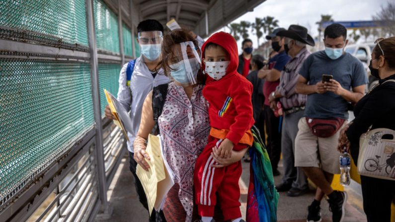 Una madre hondureña lleva a su hijo, de 4 años, a través de la frontera entre Estados Unidos y México como parte de un grupo de al menos 25 solicitantes de asilo a los que se les permitió viajar desde un campamento de migrantes en México hacia los Estados Unidos el 25 de febrero de 2021 en Matamoros, México. (John Moore/Getty Images)