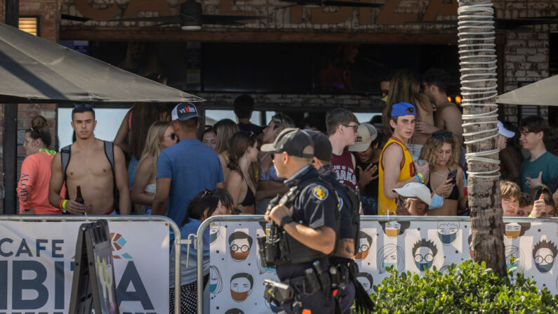 Los agentes de policía de Fort Lauderdale pasan junto a la gente que se divierte en el Café Ibiza el 4 de marzo de 2021 en Fort Lauderdale, Florida. Los estudiantes universitarios han comenzado a llegar al área del sur de Florida para el ritual anual de vacaciones de primavera. (FJoe Raedle / Getty Images)