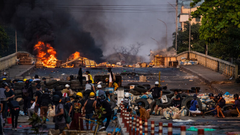El humo se eleva de neumáticos encendidos en una barricada erigida por manifestantes para detener a las fuerzas gubernamentales que cruzan un puente el 16 de marzo de 2021 en Rangún, Birmania. (Stringer / Getty Images)