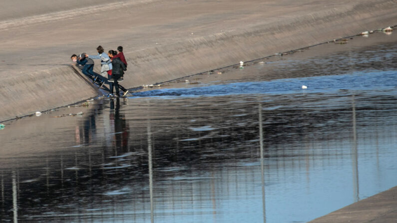 Inmigrantes indocumentados suben por un terraplén después de cruzar corriendo el Río Grande poco profundo hacia El Paso el 17 de marzo de 2021 en Ciudad Juárez, México. (John Moore/Getty Images)