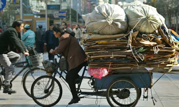 Una trabajadora migrante monta un triciclo lleno de desechos a lo largo de una calle en Shanghai, China, el 18 de febrero de 2003. (Liu Jin/AFP vía Getty Images)
