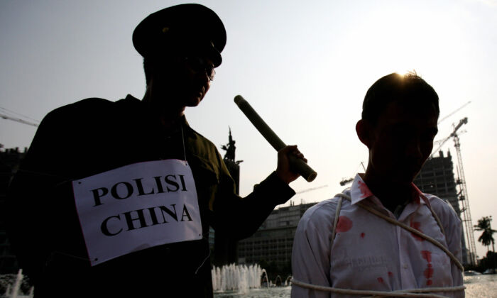 Los practicantes de Falun Gong en Yakarta, Indonesia, representan, durante una manifestación, una escena en la que la policía china tortura a un preso de conciencia, el 7 de octubre de 2006. (Adek Berry/AFP a través de Getty Images)