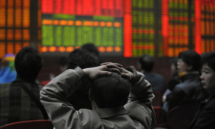 Varios inversores observan un tablero electrónico que muestra los precios de las acciones en una agencia de valores en Beijing el 20 de marzo de 2008. (Peter Parks/AFP vía Getty Images)