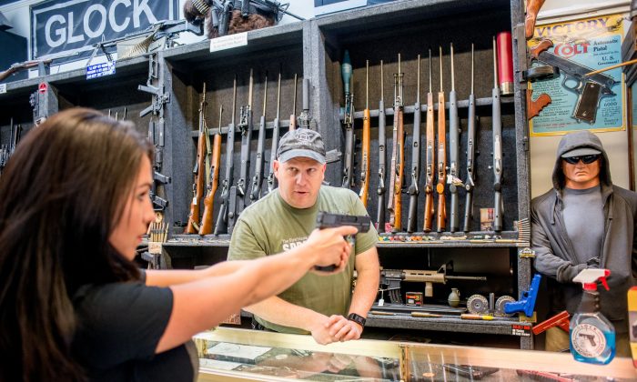 Edward Wilks, propietario de Tradesmen Gun Store and Pawnshop, ayuda a Lauren Boebert con un arma de fuego en su tienda en Rifle, Colorado, el 24 de abril de 2018. (Emily Kask/AFP/Getty Images)
