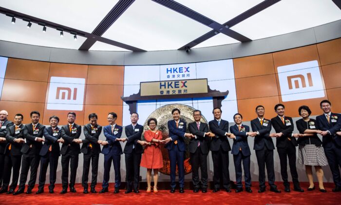 El fundador de Xiaomi, Lei Jun (en el centro, con corbata naranja), se da la mano con otros ejecutivos durante la salida a bolsa de la compañía en la HKSE en Hong Kong el 9 de julio de 2018. (Isaac Lawrence/AFP vía Getty Images)