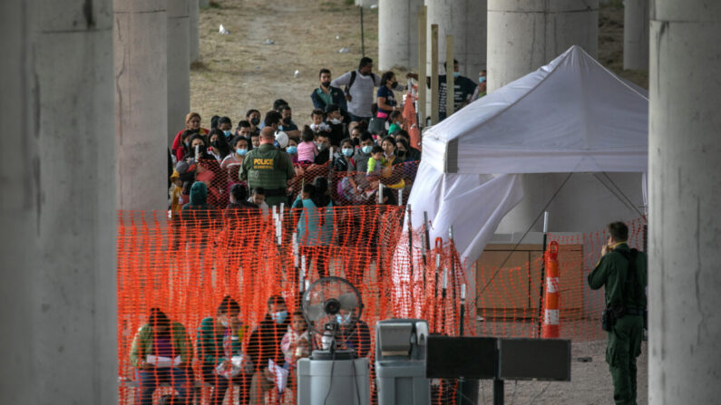 Los inmigrantes ilegales escuchan las instrucciones en un centro de procesamiento de la Patrulla Fronteriza al aire libre debajo del Puente Internacional Anzalduas después de cruzar el Río Bravo desde México cerca de Mission, Texas, el 23 de marzo de 2021. (John Moore/Getty Images)
