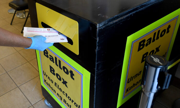 Un trabajador del Departamento de Elecciones del Condado de Clark coloca las boletas por correo, recolectadas de los vehículos, en una urna del Departamento de Elecciones del Condado de Clark, en North Las Vegas, Nevada, el 13 de octubre de 2020. (Ethan Miller/Getty Images)