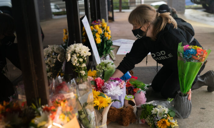 Shelby Swan ajusta las flores y los carteles fuera de Youngs Asian Massage donde cuatro personas fueron asesinadas a tiros, en Acworth, Georgia, el 17 de marzo de 2021. (Elijah Nouvelage/Getty Images)