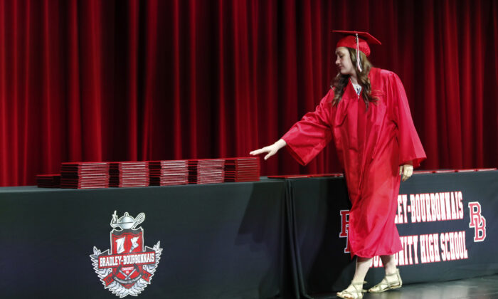 Una estudiante recoge su diploma durante una ceremonia de graduación en la Bradley-Bourbonnais Community High School el 6 de mayo de 2020, en Bradley, Ill. El diploma de la escuela secundaria frecuentemente es visto como la puerta a otras oportunidades, incluyendo la universidad y un trabajo. (KAMIL KRZACZYNSKI/AFP vía Getty Images)