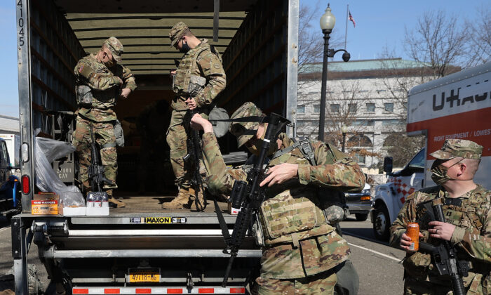 Miembros de la Guardia Nacional de EE.UU. recogen armas largas de los vehículos de almacenamiento antes de comenzar su turno de protección del Capitolio de EE.UU. en Washington el 8 de febrero de 2021. (Chip Somodevilla/Getty Images)