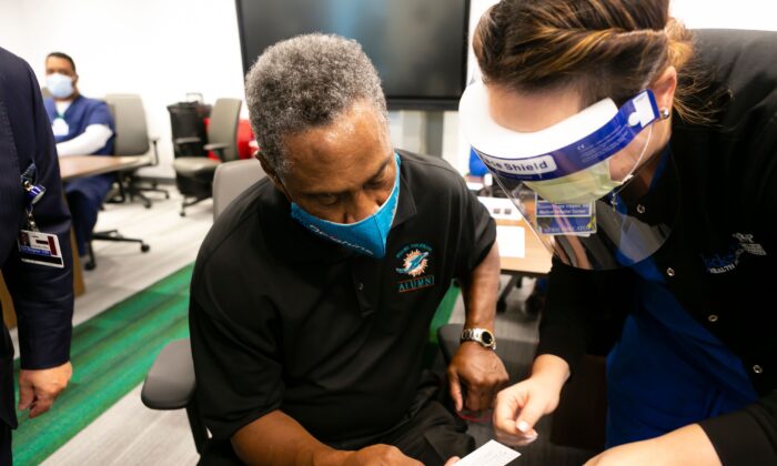 Nat Moore, de 69 años, exjugador de los Miami Dolphins, recibe su tarjeta de vacunación después de aplicarse la primera dosis de la vacuna COVID-19 de Pfizer-BioNtech en el Centro de Rehabilitación Christine E. Lynn, en Miami, Florida, el 30 de diciembre de 2020. (Eva Marie Uzcategui/AFP vía Getty Images)