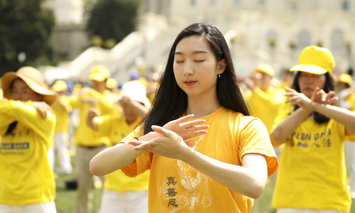 Practicantes de Falun Gong realizan ejercicios de meditación en un mitin que conmemora el vigésimo aniversario de la persecución a Falun Gong en China, en el jardín oeste del Capitolio, el 18 de julio de 2019. (Samira Bouaou/The Epoch Times).