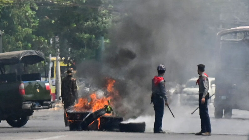 La policía está parada junto a una barricada de neumáticos improvisada en llamas, erigida por manifestantes que se manifestaban contra el golpe militar, en el municipio de Rangún, Birmania, en el sur de Okkalapa el 1 de abril de 2021. (STR / AFP vía Getty Images)