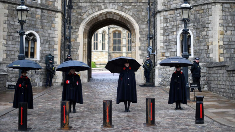 Los guardianes del castillo se resguardan de la lluvia bajo paraguas fuera del castillo de Windsor en Windsor, al oeste de Londres, el 10 de abril de 2021, el día después de la muerte del príncipe británico Felipe, duque de Edimburgo, a la edad de 99. (Daniel Leal-Olivas/AFP vía Getty Images)