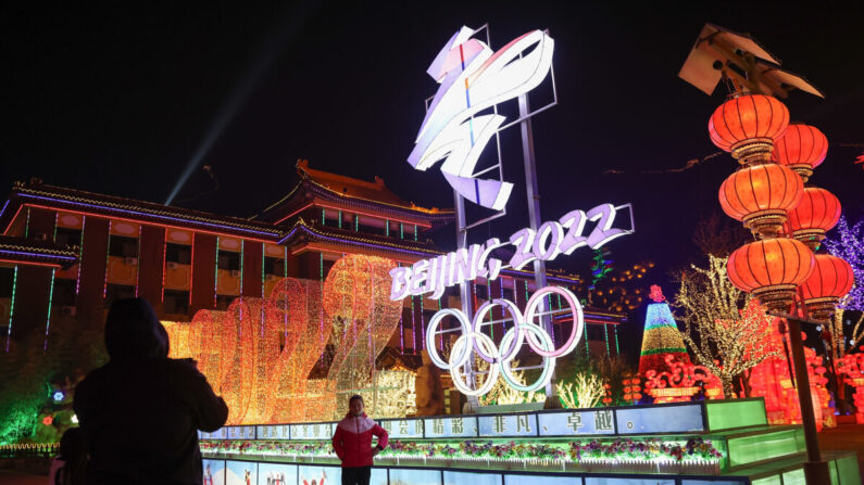 Las personas usan mascarillas protectoras mientras caminan frente a los logotipos de los Juegos Olímpicos de Invierno de Beijing 2022 en el Festival de Hielo Yanqing en Beijing, China, el 26 de febrero de 2021. (Lintao Zhang/Getty Images)