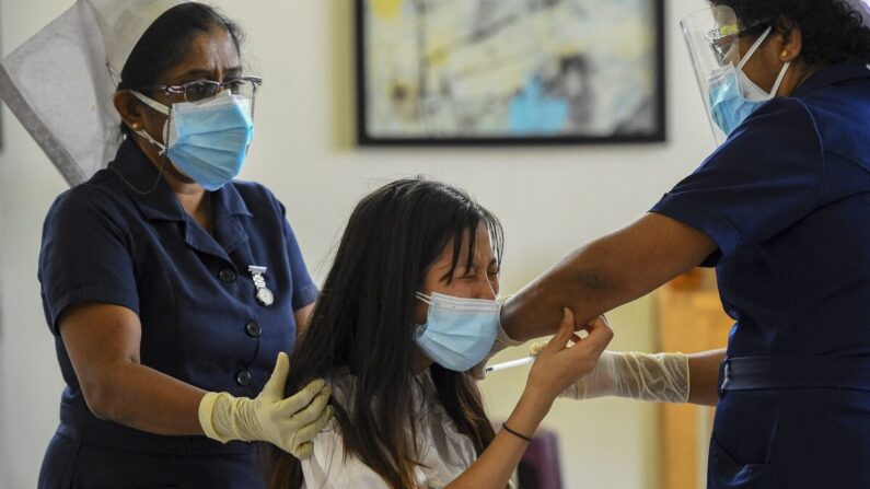 Un trabajador sanitario inocula la vacuna de fabricación china Sinopharm a un ciudadano chino que vive en Sri Lanka, en las instalaciones del proyecto Colombo Port City, en Colombo, Sri Lanka, el 6 de abril de 2021. (Ishara S. Kodikara/AFP vía Getty Images)
