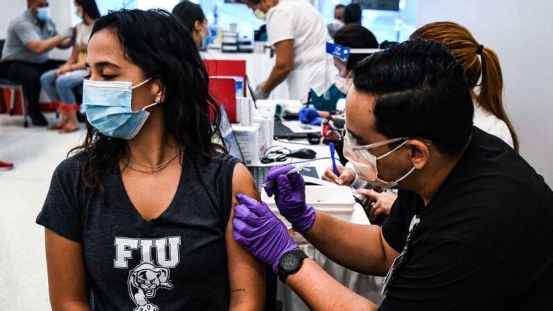 El estudiante de farmacia Jason Rodríguez (d) administra una vacuna contra covid-19 a la boliviana Camila Gutiérrez (i) en el Centro de Rehabilitación Christine E. Lynn en Miami, Florida (EE.UU.), el 15 de abril de 2021. (Chandan Khanna/AFP vía Getty Images)