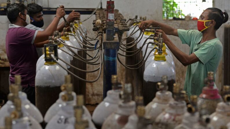 Trabajadores llenan botellas de oxígeno médico para ser transportadas a los hospitales en medio de la pandemia del covid-19 en una instalación en las afueras de Chennai (India) el 24 de abril de 2021. (Arun Sankar/AFP vía Getty Images)