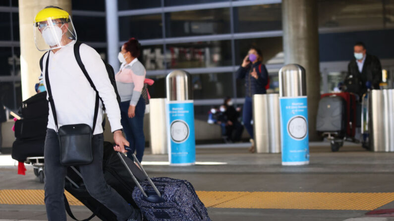 Un viajero camina con equipaje fuera de la Terminal Internacional Tom Bradley en el Aeropuerto Internacional de Los Ángeles (LAX) en medio de una oleada de COVID-19 en el sur de California el 22 de diciembre de 2020 en los Ángeles, California. (Mario Tama / Getty Images)