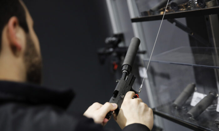Un visitante tira de la corredera de una pistola con silenciador en una exhibición de armas en la feria comercial de deportes al aire libre de la Asociación Nacional del Rifle en Harrisburg, Pensilvania, el 10 de febrero de 2017. (Dominick Reuter/AFP a través de Getty Images)