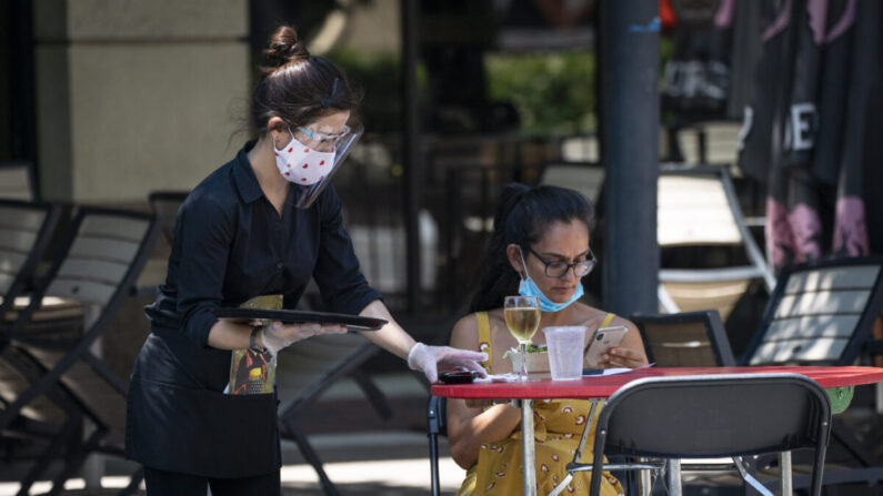 Una camarera de Raku, un restaurante asiático en Bethesda, usa una mascarilla mientras sirve a los clientes al aire libre en medio de la pandemia de coronavirus en Bethesda, Maryland, el 12 de junio de 2020. (Sarah Silbiger/Getty Images)

