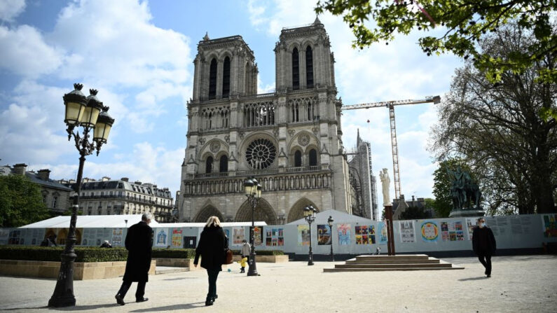 La gente camina frente a la catedral de Notre-Dame de París, el 14 de abril de 2021, durante las obras de reconstrucción, mientras que el 15 de abril de 2021 se cumplirán dos años del incendio que devastó la catedral, en el centro de la capital francesa, París. (Anne-Christine POUJOULAT / AFP vía Getty Images)