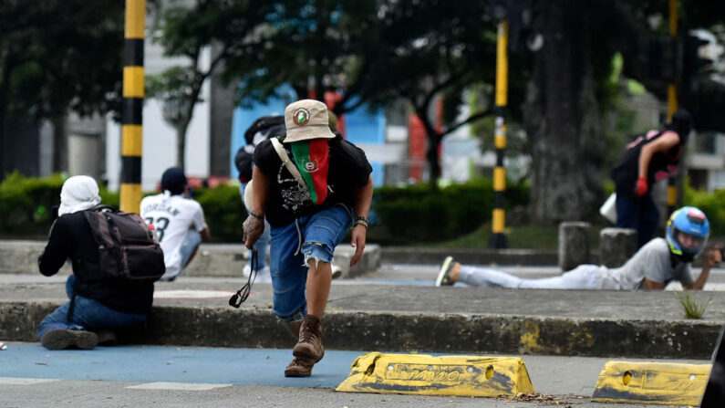 Manifestantes se cubren de las balas durante enfrentamientos con la policía en el marco de una nueva protesta contra el gobierno del presidente colombiano Iván Duque, en Cali, Colombia, el 28 de mayo de 2021. (Luis Robayo/AFP vía Getty Images)