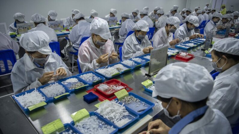 Los trabajadores ensamblan piezas para los cigarrillos electrónicos en la línea de producción de KangerTech, uno de los principales fabricantes chinos de productos de vapeo en Shenzhen, China, el 24 de septiembre de 2019. (Kevin Frayer/Getty Images)