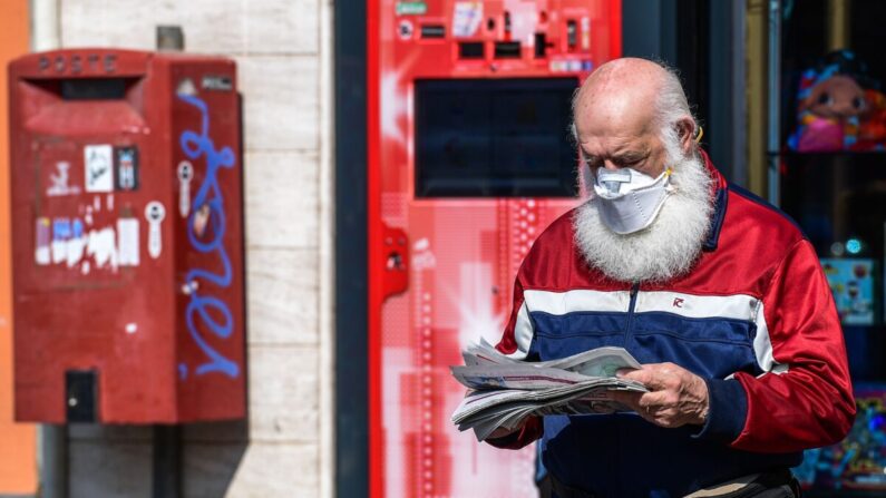 Un residente con una mascarilla sale de una tienda después de comprar un periódico en Treviolo, Italia, el 9 de abril de 2020. (Miguel Medina/AFP vía Getty Images)