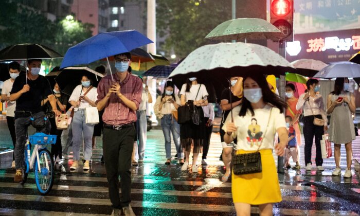 Personas con mascarillas protectoras caminan con paraguas bajo la lluvia en Shenzhen, provincia de Guangdong, al sur de China, el 22 de mayo de 2020. (NOEL CELIS/AFP vía Getty Images)