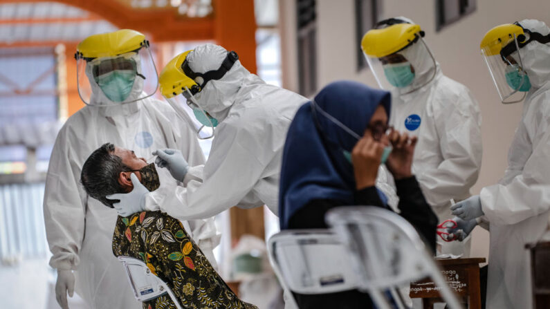 Trabajadores médicos con equipo de protección recogen pruebas de hisopo de un hombre para la enfermedad del COVID-19 durante la prueba masiva en el internado islámico de Sunan Pandanaran el 29 de julio de 2020 en Yogyakarta, Indonesia. (Ulet Ifansasti/Getty Images)