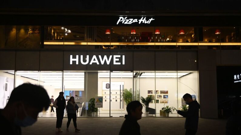 Gente pasa frente a una tienda Huawei debajo de un Pizza Hut en Beijing el 22 de octubre de 2020. (GREG BAKER/AFP a través de Getty Images)