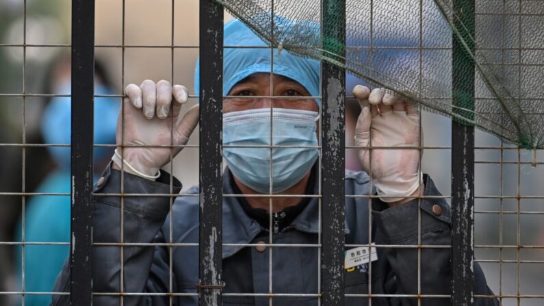 Un trabajador con una mascarilla mira desde la entrada de un hospital hacia el Centro para el Control y la Prevención de Enfermedades en Wuhan, en la provincia central de Hubei en China, el 1 de febrero de 2021. (Héctor Retamal/AFP a través de Getty Images)