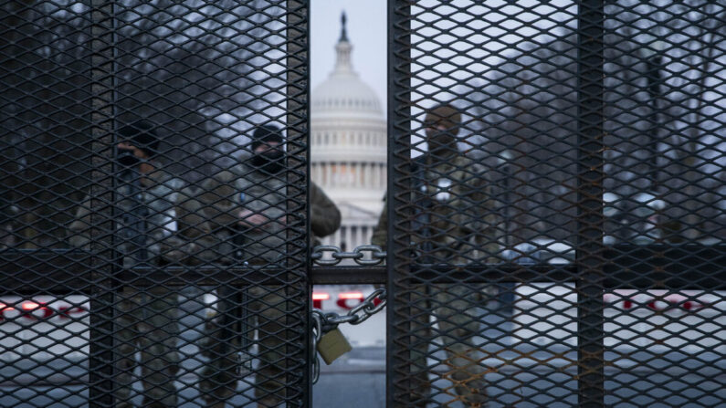 Antes del amanecer, miembros de la Guardia Nacional se sitúan detrás de una valla de alambre de púas que rodea el Capitolio en Washington el 4 de marzo de 2021. (Sarah Silbiger/Getty Images)