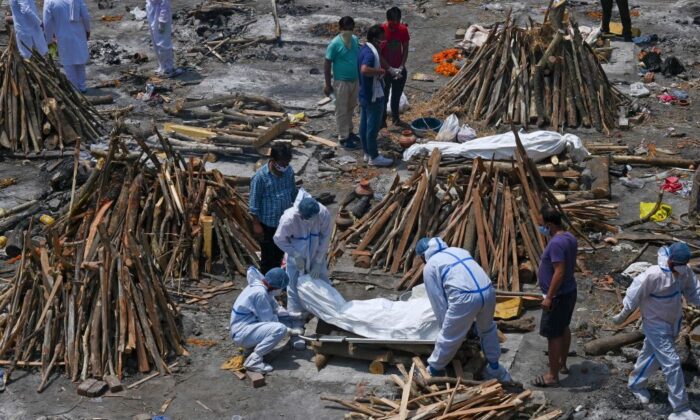 Los miembros de la familia y los trabajadores de ambulancia que usan un EPP (equipo de protección personal) llevan los cuerpos de los pacientes que murieron por COVID-19 en un campo de cremación en Nueva Delhi, India, el 27 de abril de 2021. (Prakash Singh/AFP a través de Getty Images)