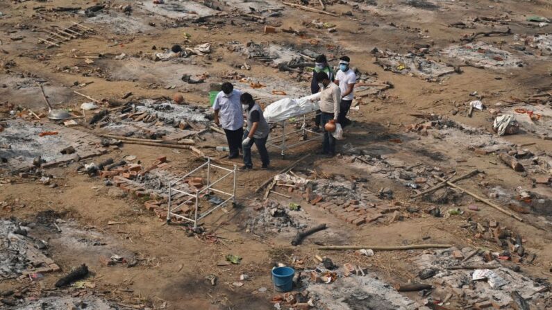 Familiares llevan el cuerpo de una víctima que murió a causa del COVID-19 en un campo de cremación en Nueva Delhi el 2 de mayo de 2021. (TAUSEEF MUSTAFA/AFP vía Getty Images)