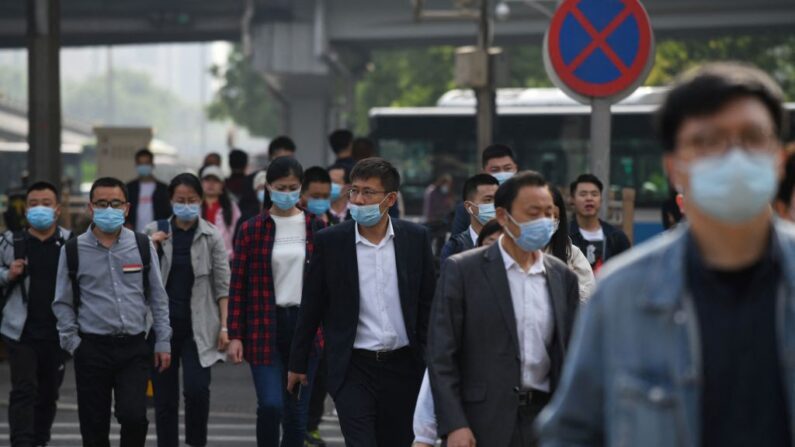 Los transeúntes cruzan una calle durante la hora punta de la mañana en Beijing (China) el 11 de mayo de 2021. (Greg Baker/AFP vía Getty Images)