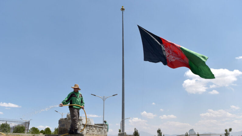 Un trabajador riega un césped cerca de una bandera nacional afgana que ondea a media asta en Kabul el 11 de mayo de 2021. El presidente afgano Ashraf Ghani declaró el 11 de mayo día nacional de luto para condenar los recientes ataques terroristas. (WAKIL KOHSAR/AFP a través de Getty Images)