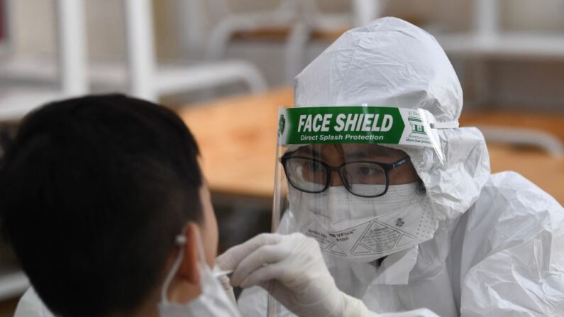 Un trabajador sanitario con equipo de protección personal (EPP) realiza una prueba de hisopo del covid-19 a un estudiante en la escuela privada Vinschool en Hanói (Vietnam) el 22 de mayo de 2021. (Nhac Nguyen / AFP vía Getty Images)