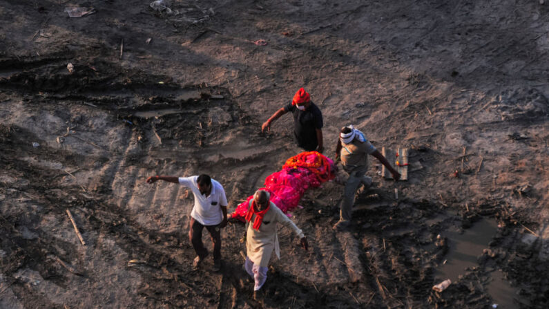 Familiares llevan el cuerpo de un pariente que se cree que murió de COVID-19 a una pira funeraria en un sitio de cremación masiva en las orillas del río Ganges el 05 de mayo de 2021 en Allahabad, India. (Ritesh Shukla/Getty Images)
