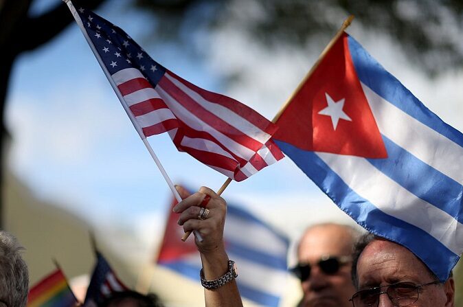 Una manifestante sostiene una bandera estadounidense y una cubana mientras se une a otras personas que se oponen al anuncio del presidente estadounidense Barack Obama a principios de la semana de un cambio en la política de Estados Unidos hacia Cuba, en el parque José Martí el 20 de diciembre de 2014 en Miami, Florida. (Joe Raedle/Getty Images)
