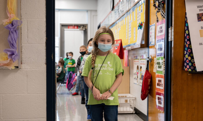 Un grupo de alumnos con mascarilla espera en una fila única respetando la distancia social antes de dirigirse a la cafetería de una escuela primaria en Louisville (Kentucky) el 17 de marzo de 2021. (Jon Cherry/Getty Images)