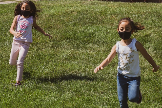 Un par de niñas corren y juegan mientras usan mascarilla entorno a la pandemia por COVID-19. (Atoms/Unsplash)