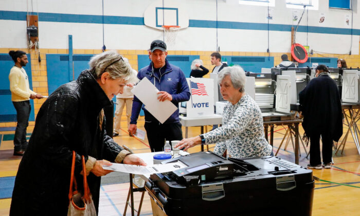 En una foto de archivo, varias personas introducen sus votos en una máquina de conteo. (Jeff Kowalsky/AFP vía Getty Images)
