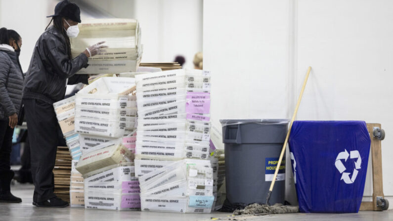 Un trabajador del Departamento de Elecciones de Detroit ayuda a apilar las cajas vacías que se utilizaron para organizar las papeletas de voto ausente, después de acercarse al final del conteo de votos ausentes en la Junta Central de Conteo, en el TCF Center en Detroit, Michigan, el 4 de noviembre de 2020. (Elaine Cromie/Getty Images)