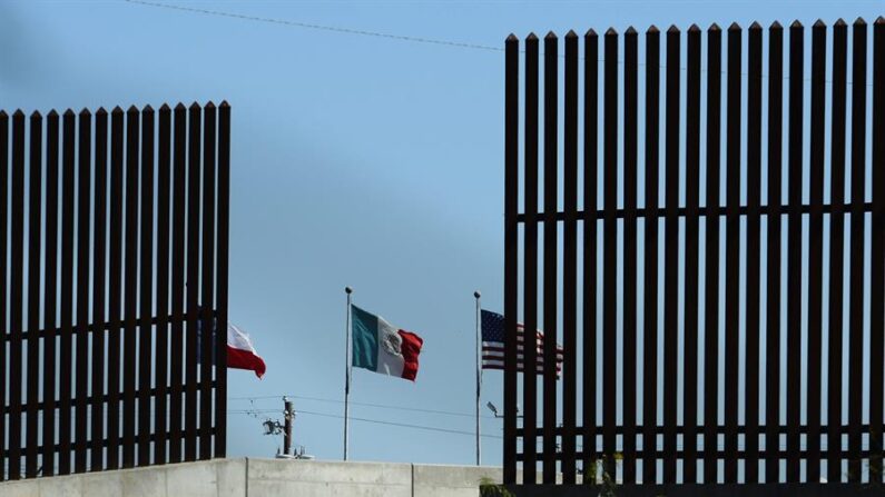 Fotografía de banderas a través del muro de seguridad cerca de McAllen, Texas (EE.UU.). EFE/Larry W. Smith/Archivo
