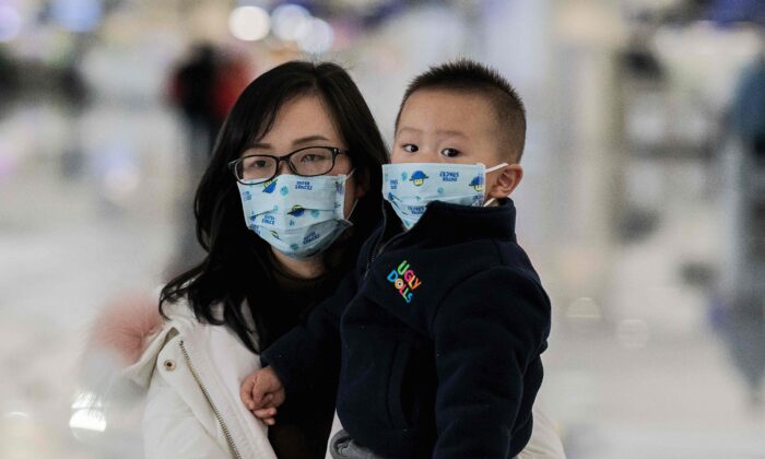 Una mujer y un niño con mascarillas protectoras caminan hacia los mostradores de facturación en el aeropuerto internacional de Daxing, en Beijing, el 21 de enero de 2020. (Nicolas Asfouri/AFP a través de Getty Images)