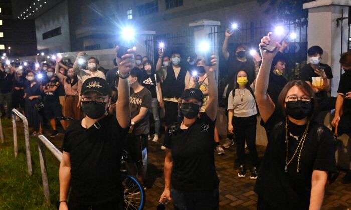Seguidores del periódico hongkonés Apple Daily agitan las luces de sus teléfonos móviles frente a la sede de la compañía en Hong Kong el 23 de junio de 2021. (Sung Pi-lung/The Epoch Times)