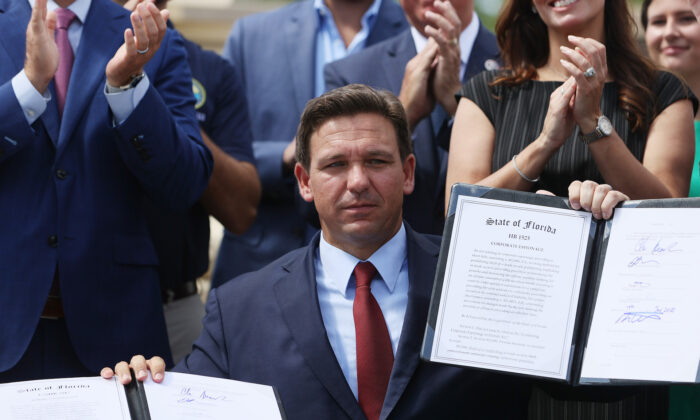 El gobernador de Florida, Ron DeSantis, sostiene dos proyectos de ley que firmó en la Armería Robert A. Ballard de la Guardia Nacional de Florida en Miami, Florida, el 7 de junio de 2021. (Joe Raedle/Getty Images)
